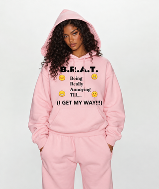 Model in pink B.R.A.T. hoodie and pink sweatpants, hood up